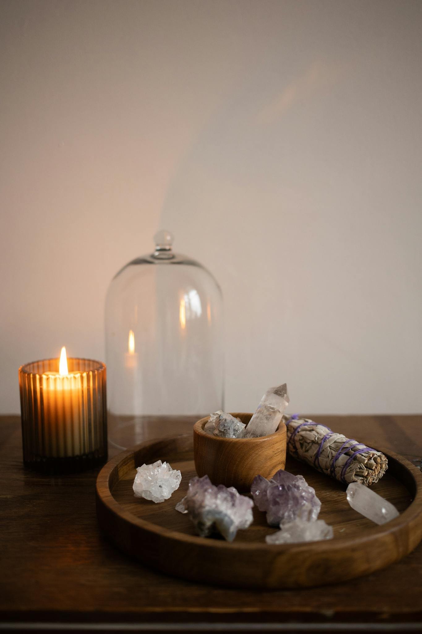 Calm meditation setup with healing crystals, candle, and sage smudge stick for relaxation.