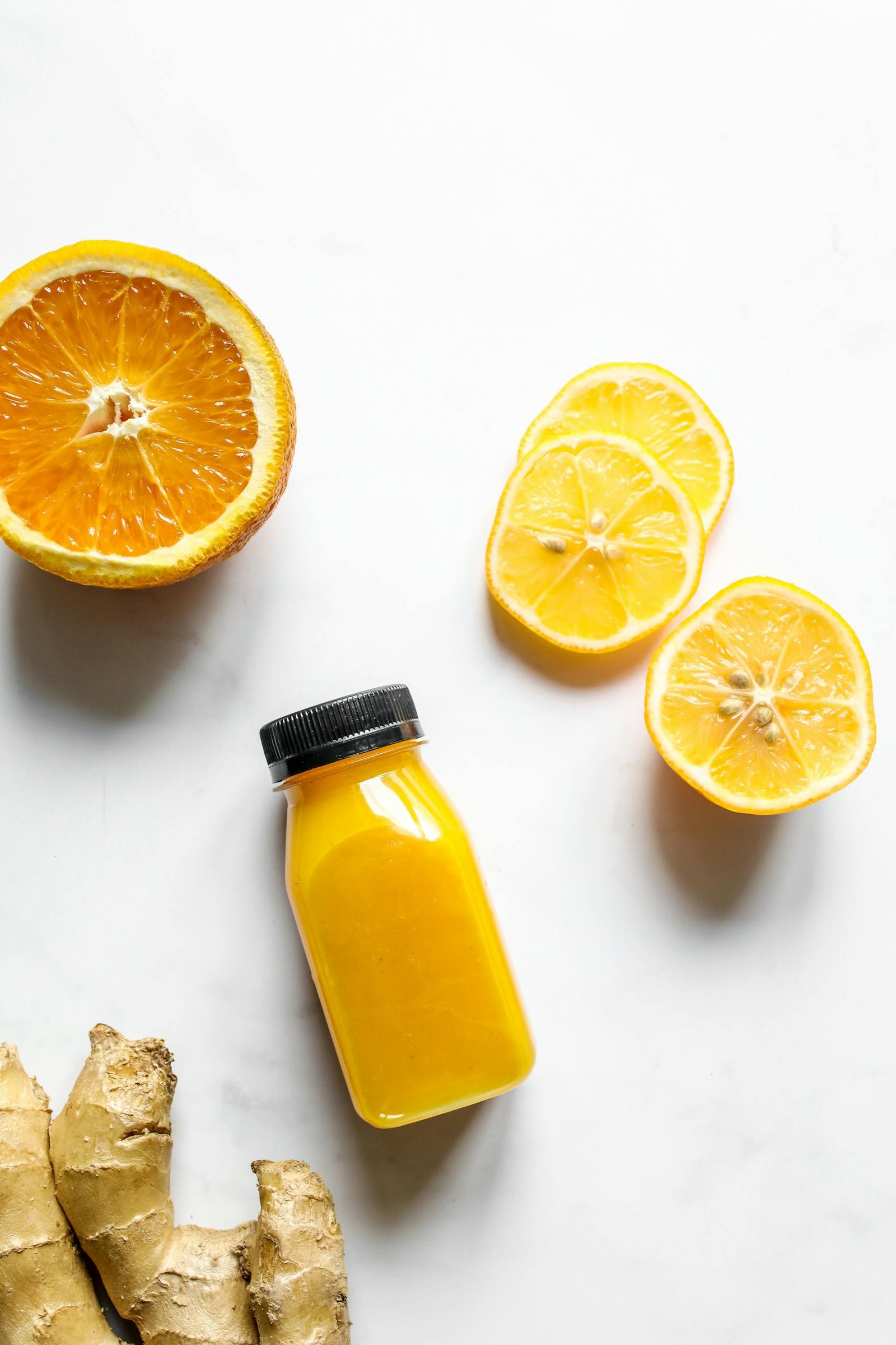 Top view of a citrus and ginger juice bottle with fresh orange and lemon slices, perfect for a healthy boost.