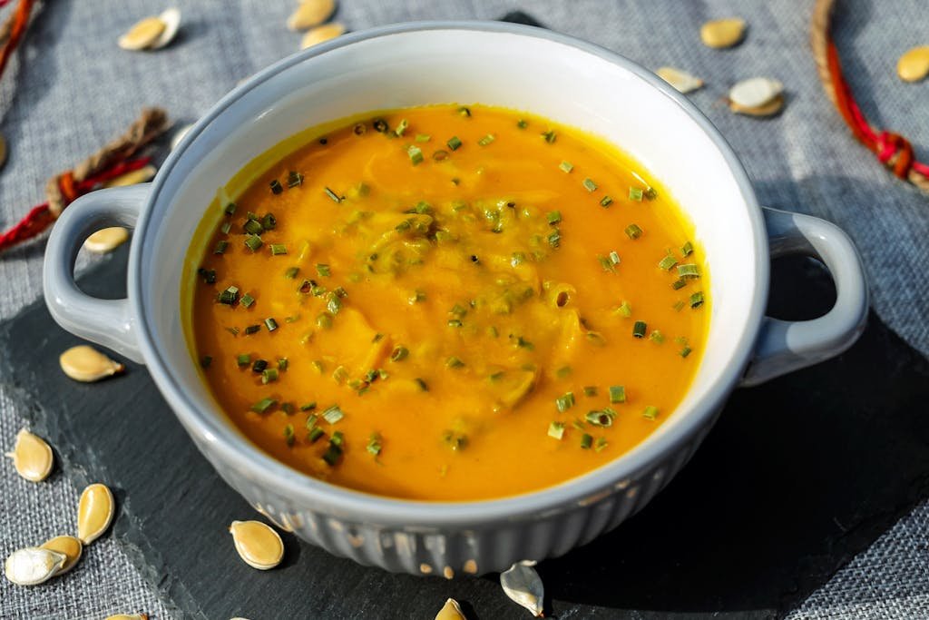 Warm and creamy pumpkin soup garnished with fresh herbs, perfect for a cozy meal.